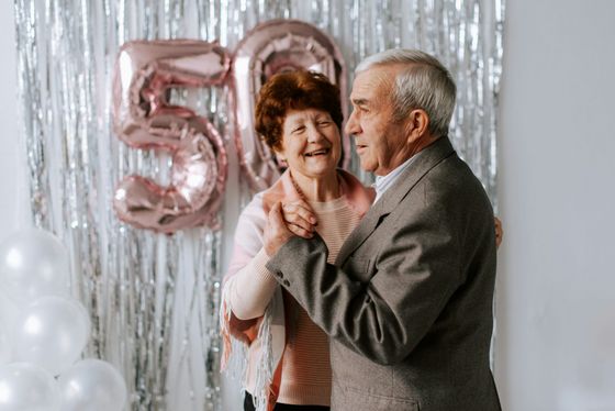 An elderly couple is dancing at a birthday party.