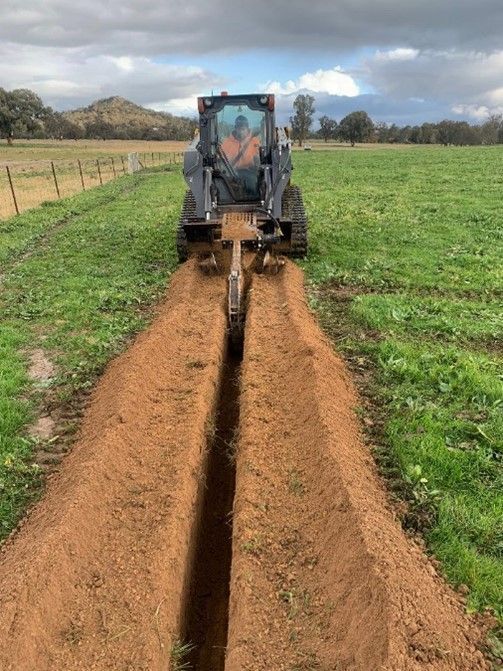 A tractor is digging a trench in a field.