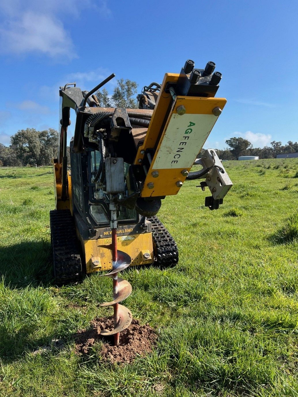 A yellow tractor is digging a hole in the grass.