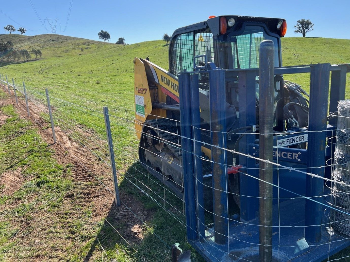 A tractor is behind a barbed wire fence in a field