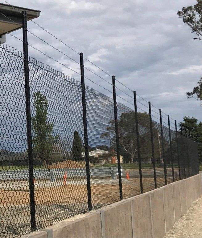 A man is working on a fence in a grassy field.
