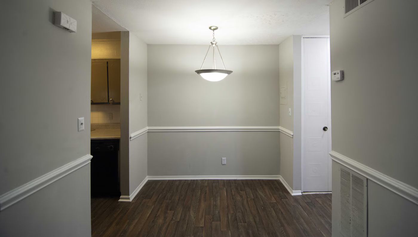 Dining room with gray walls, dark wood floor, and a hanging light.