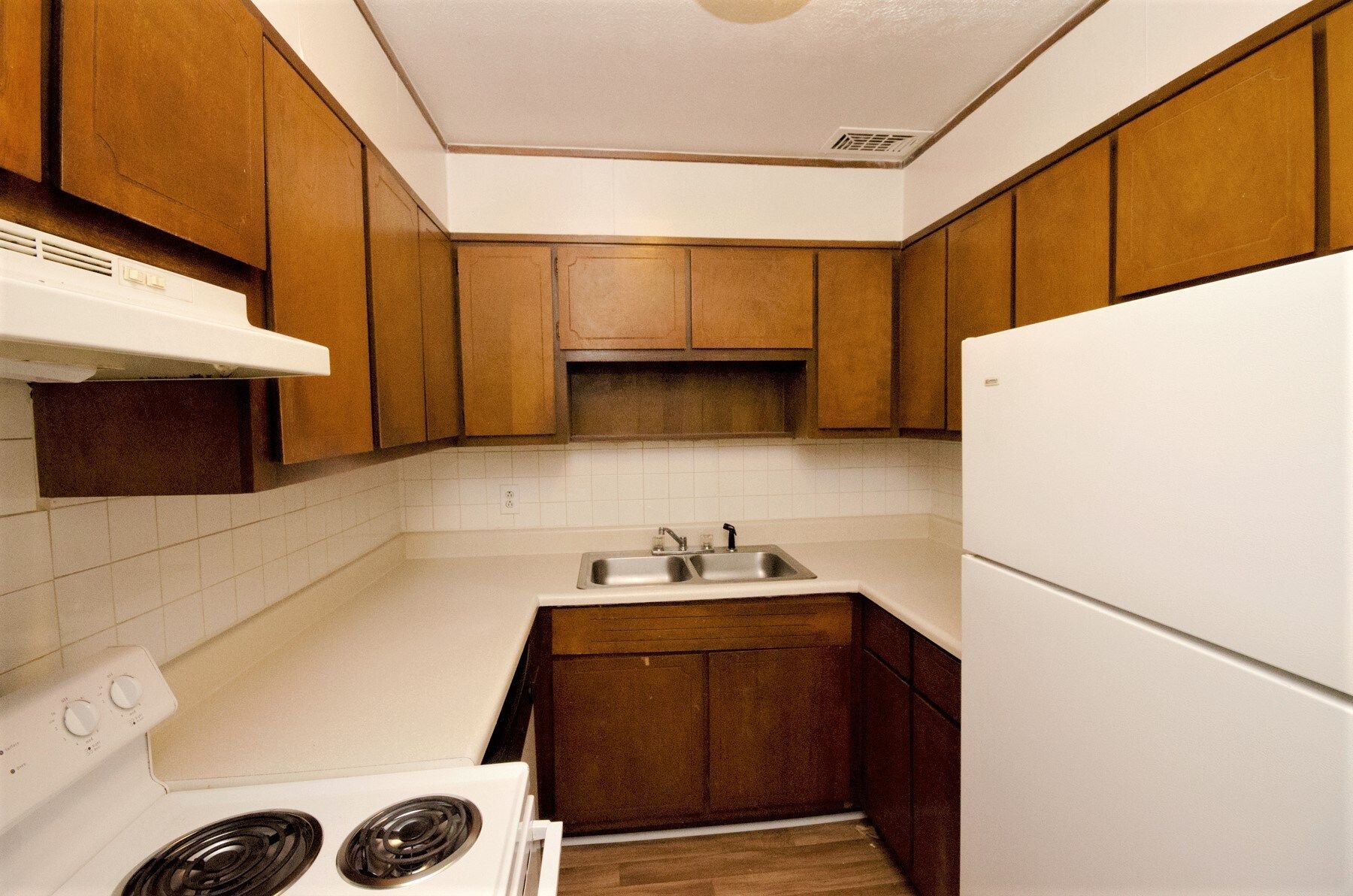 Kitchen with brown cabinets, white appliances, and a white countertop.