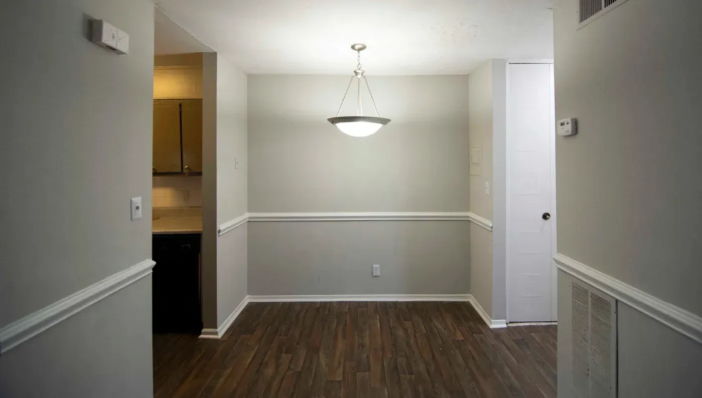 Dining room with gray walls, white trim, wood floor, and hanging light fixture.