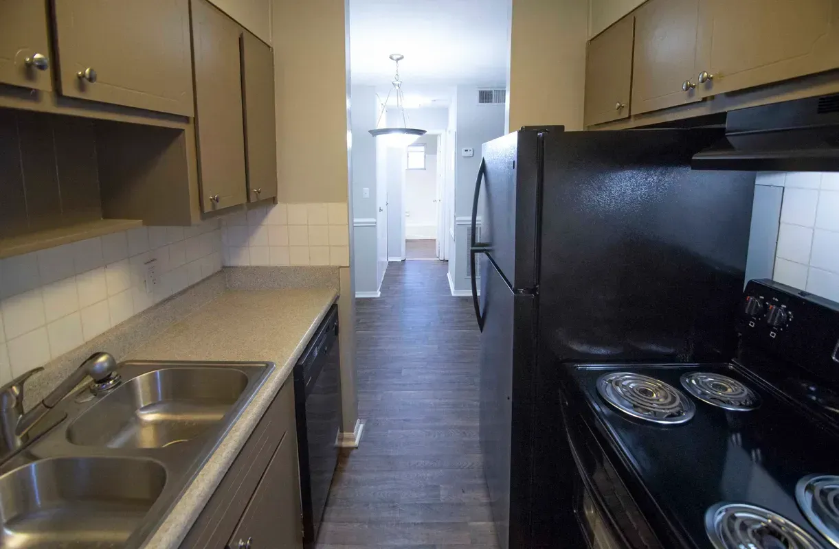 Kitchen with light countertops, dark appliances, and a hallway view.
