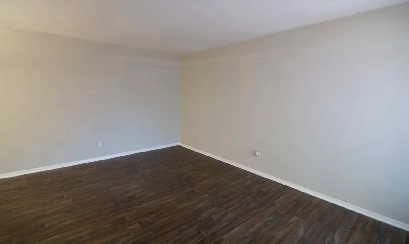 Empty room with wood-look flooring and beige walls.