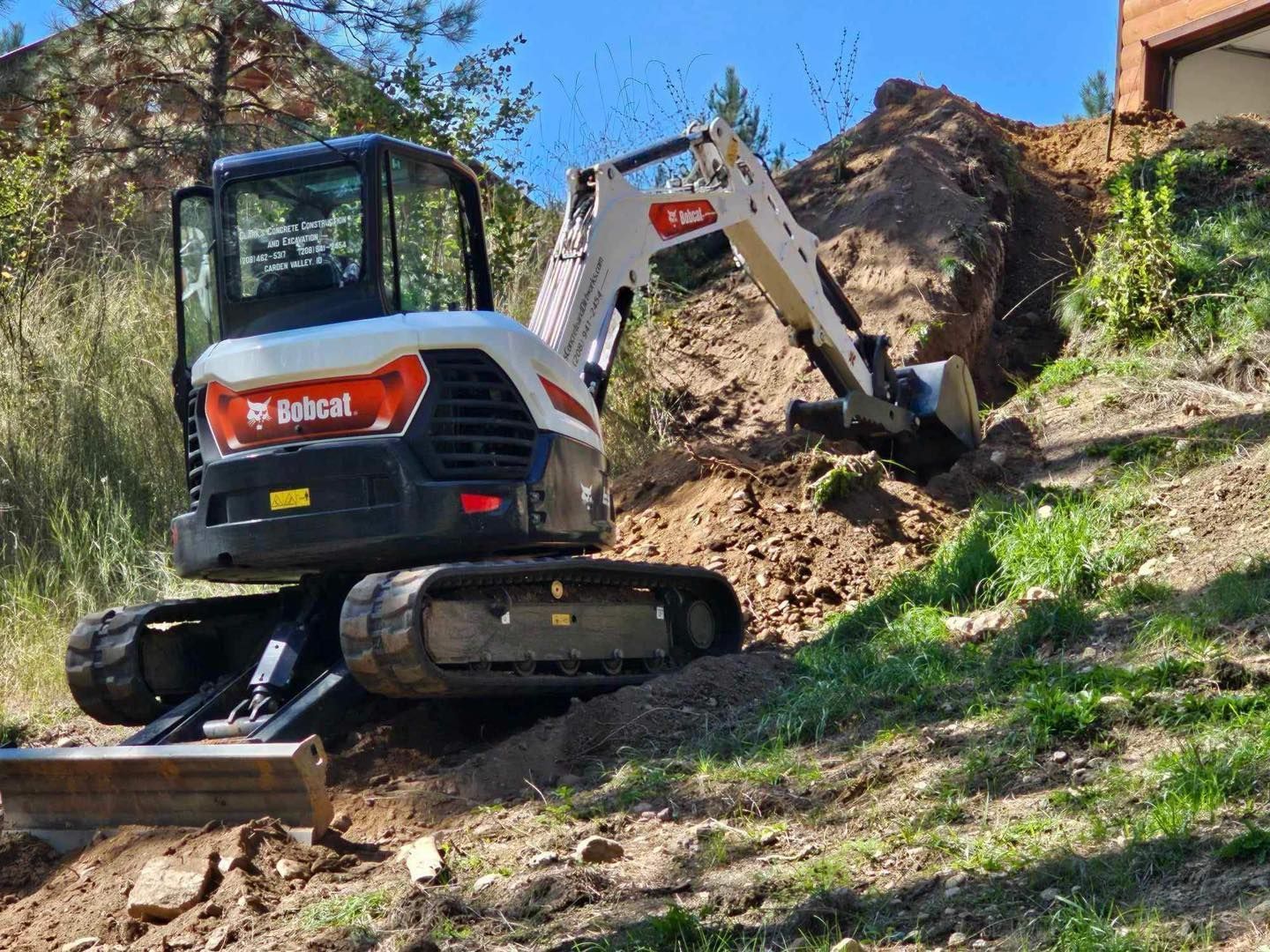 A bobcat is digging a hole in a grassy field.
