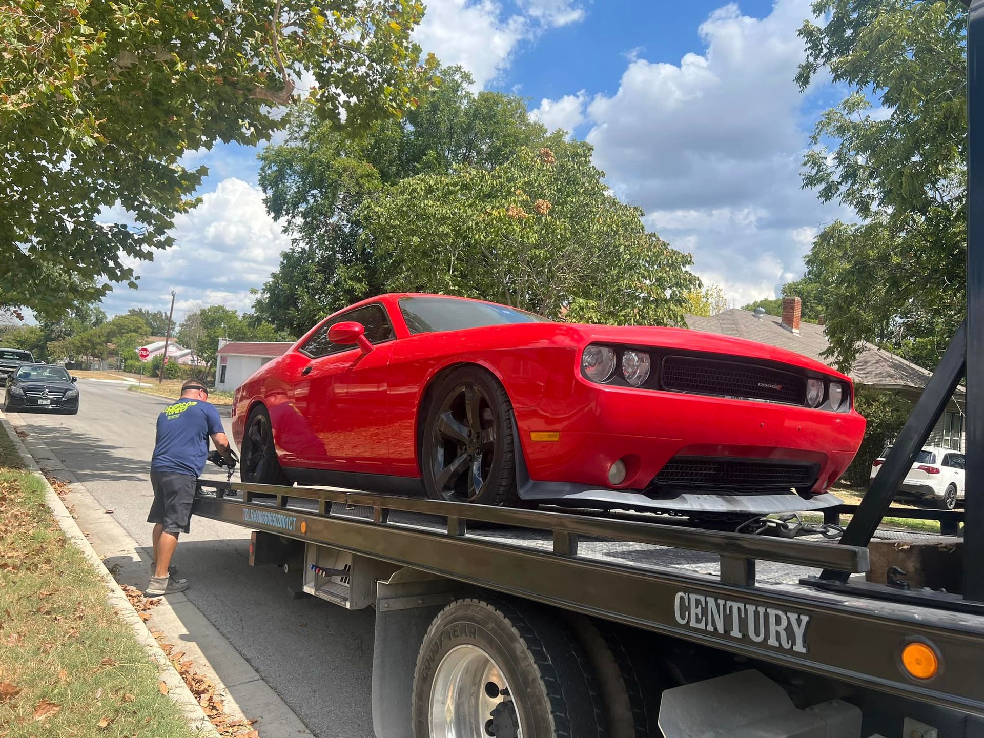 A red car is being towed by a century tow truck.