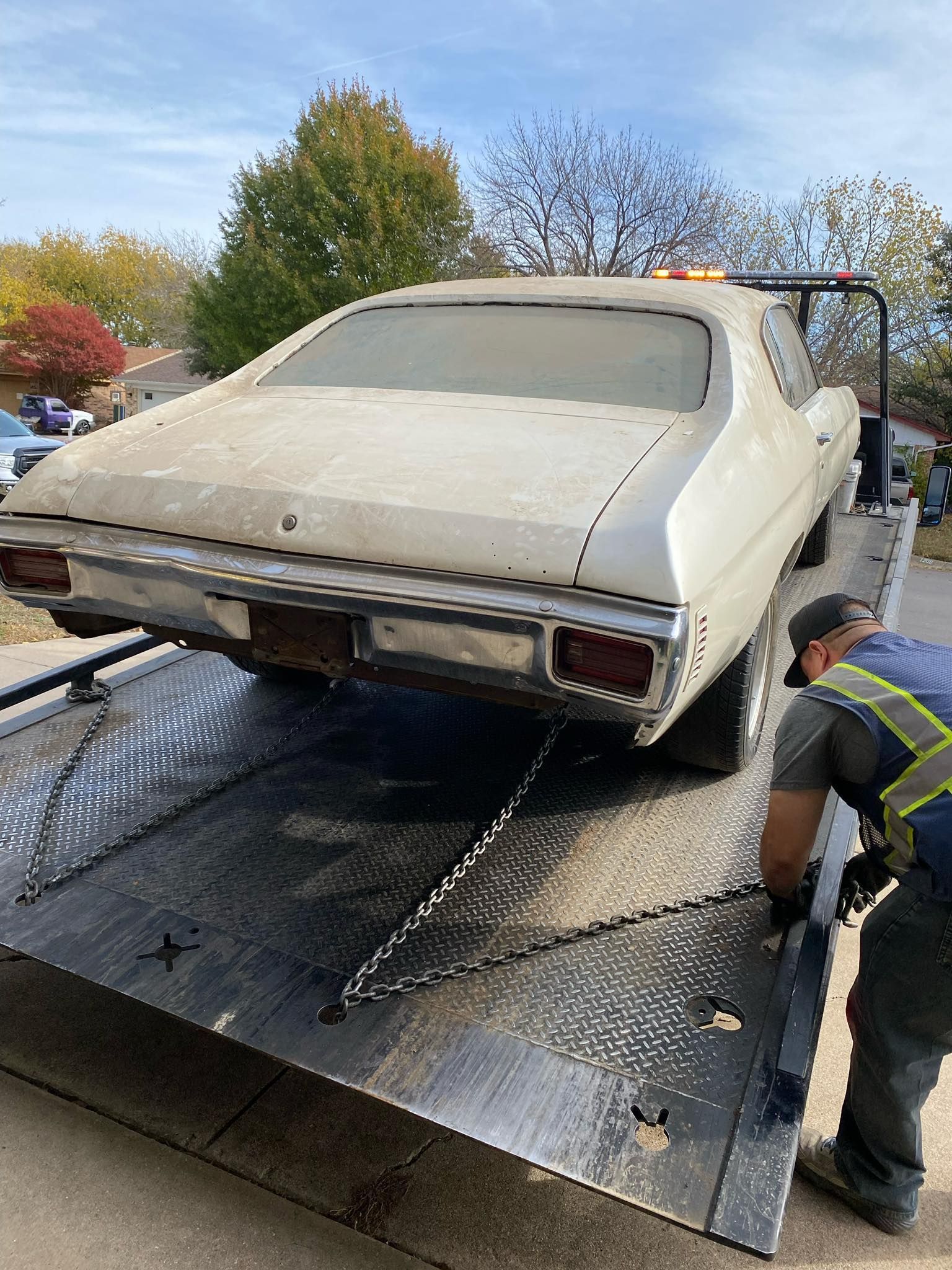A man is towing a white car on a tow truck.