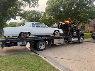 A white car is being towed by a tow truck.