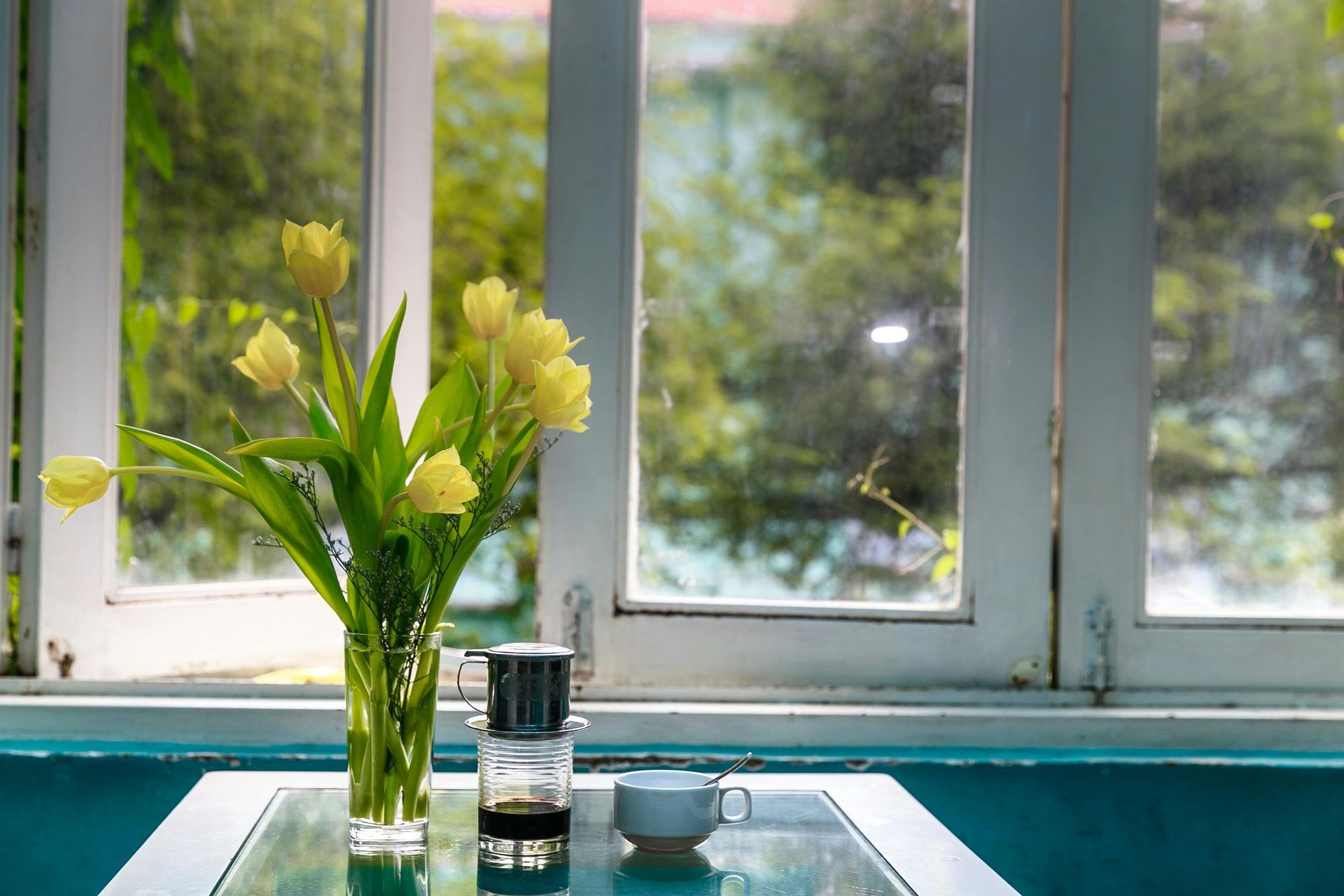 A vase of flowers is sitting on a table in front of a window.