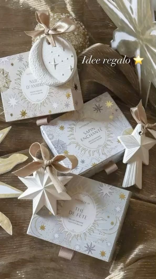 Scatole e decorazioni a forma di stella su una superficie marrone, impreziosita da dettagli dorati e bianchi.