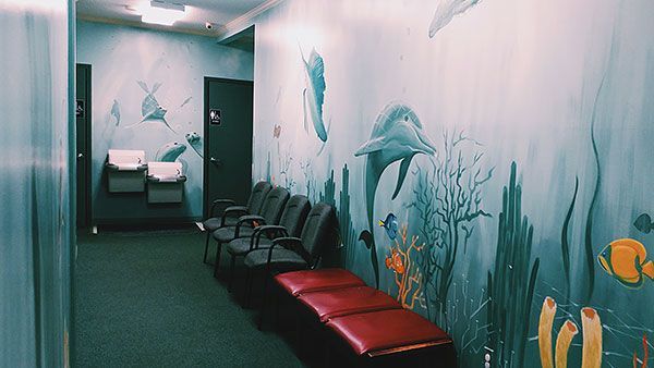 A waiting room with a painting of dolphins on the wall.