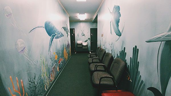 A long hallway with chairs and a mural on the wall.