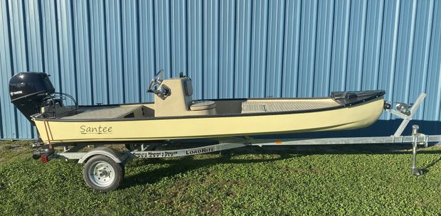 Blue and white motorboat on a trailer, with blue canopy, parked outdoors next to a building.