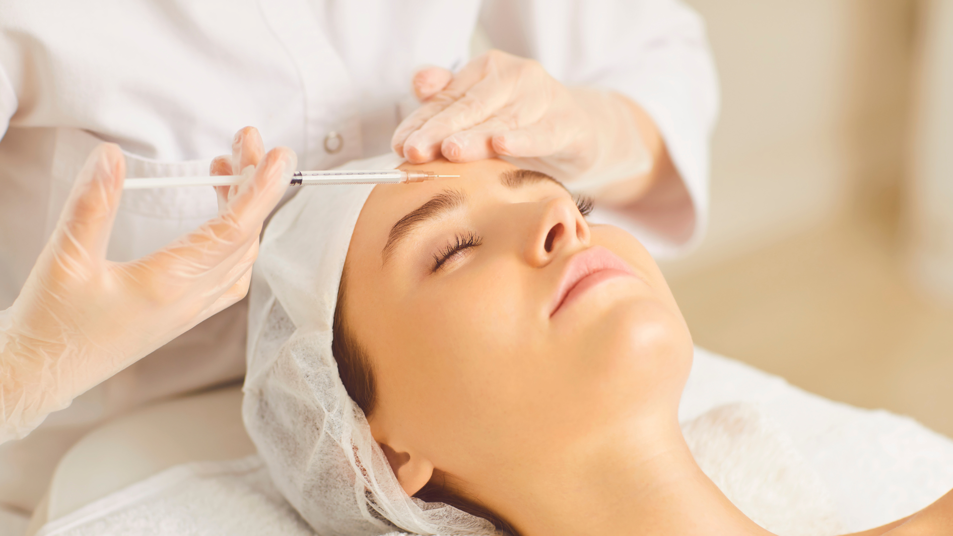 A woman is getting a botox injection on her forehead.