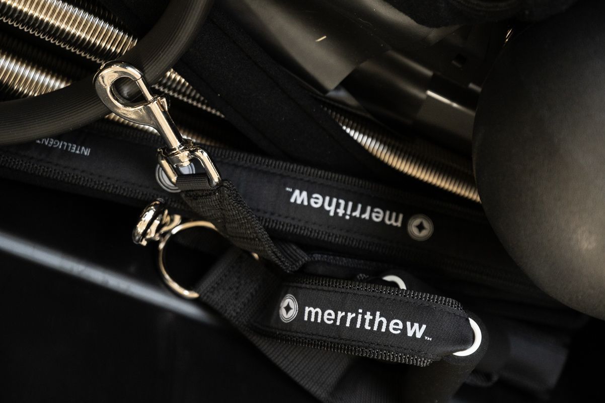 Black Pilates equipment with a strap and keychain that say 