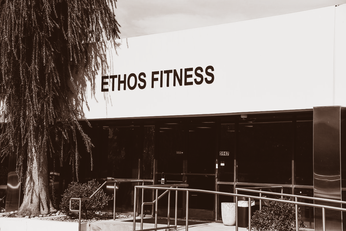 Two people using battle ropes in a dimly lit gym, performing a workout.