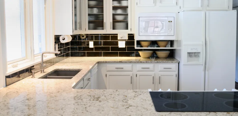 A kitchen with white cabinets , granite counter tops , a refrigerator , sink and stove.