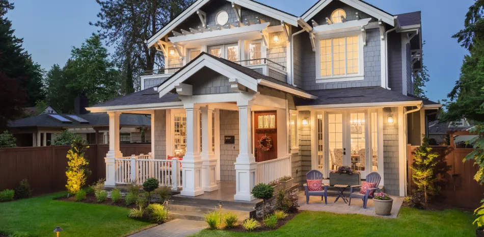 A large house with a large porch is lit up at night.