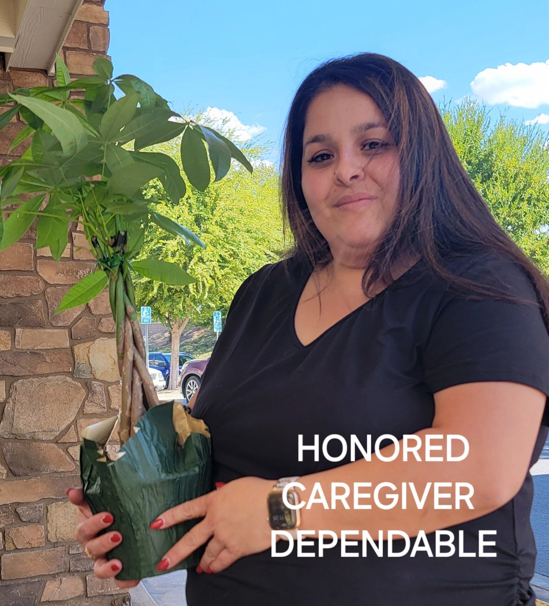 A woman in a black shirt is holding a potted plant.
