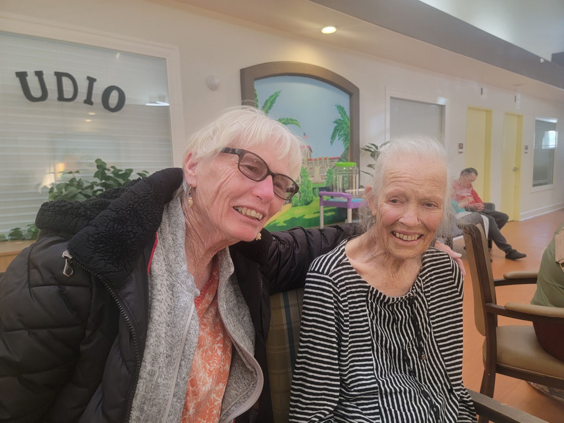 Two women are posing for a picture in a nursing home.
