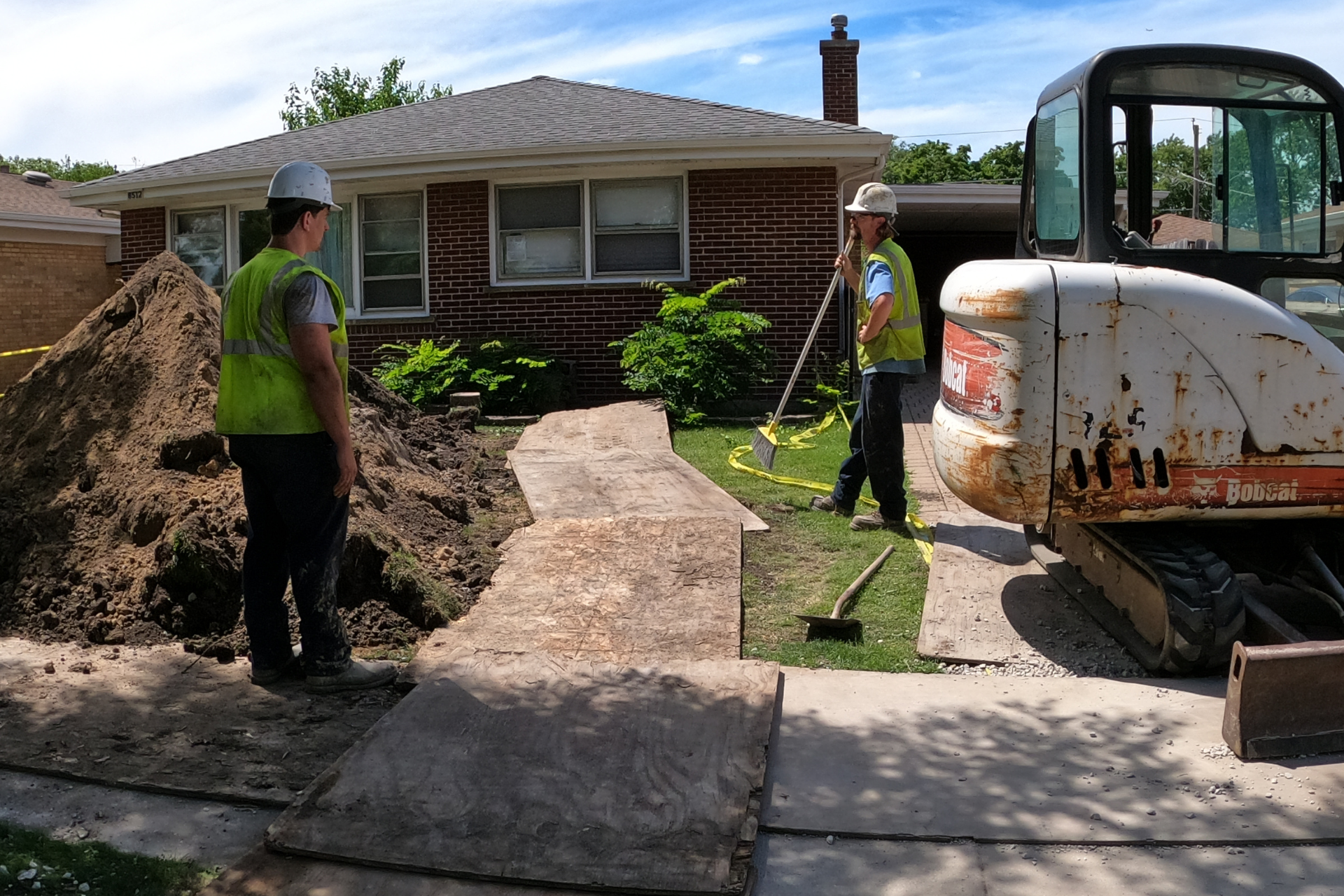 Two plumbers are working on a sidewalk in front of a house in Chicago.