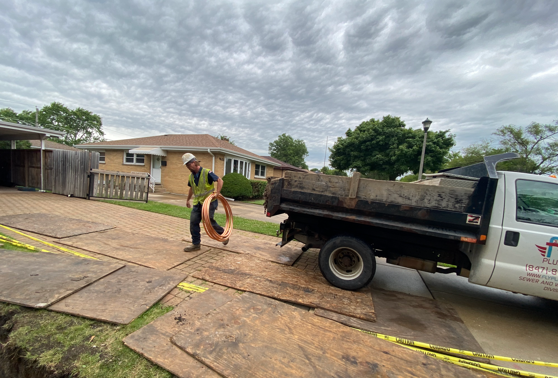 A dump truck is parked in a driveway next to a house.