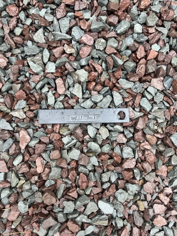 Gravel with red, gray, and light brown colors. A ruler rests in the middle for scale.