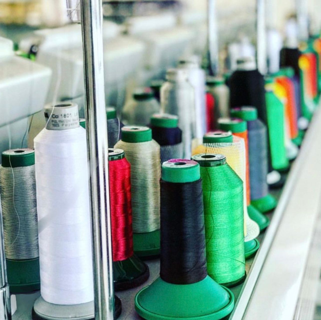 Many spools of thread are lined up on a rack