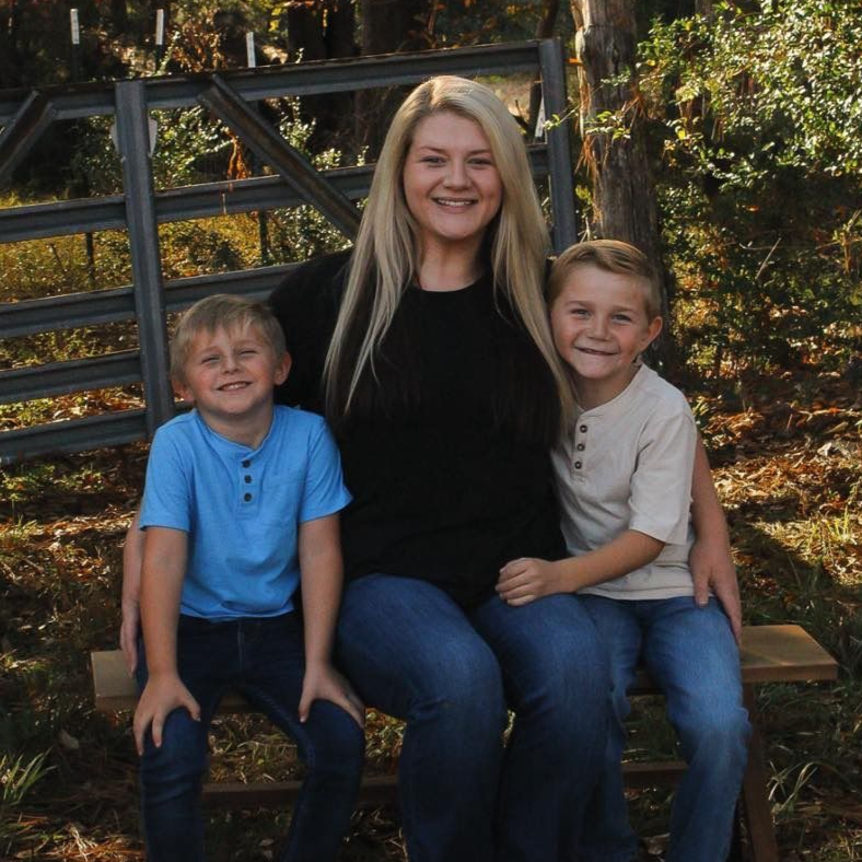 A woman in a striped sweater is standing next to two young boys.