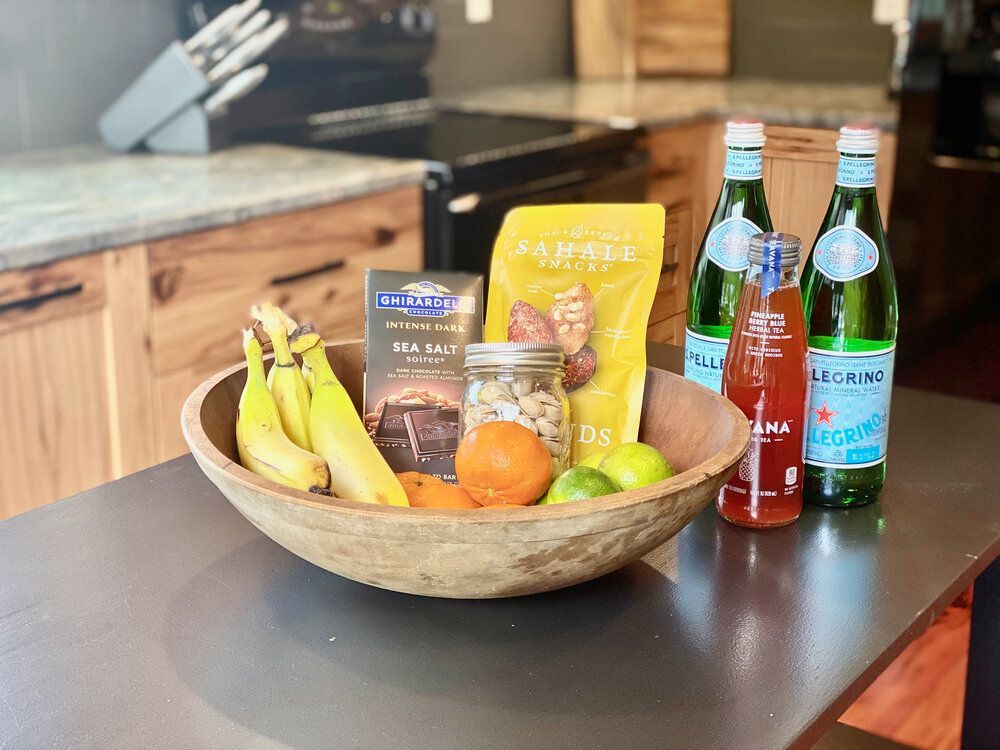 A bowl of fruit is sitting on a kitchen counter next to bottles of water.