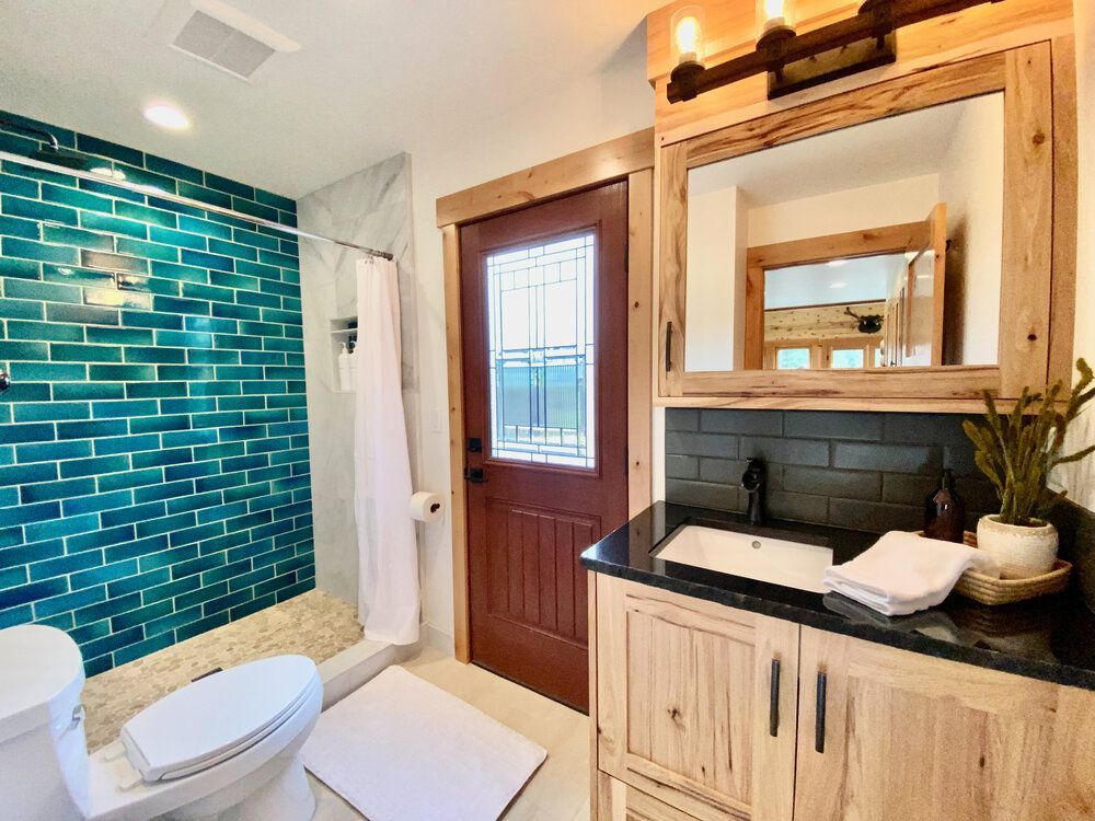 A bathroom with a toilet, sink, shower, and mirror.