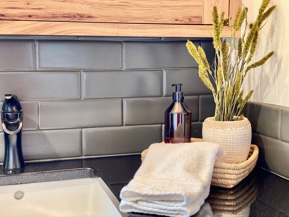 A bathroom with a sink, soap, towels and a potted plant.