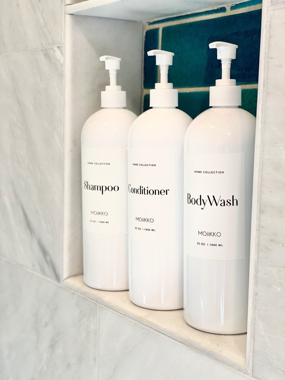 Three bottles of soap sitting on a shelf in a bathroom.