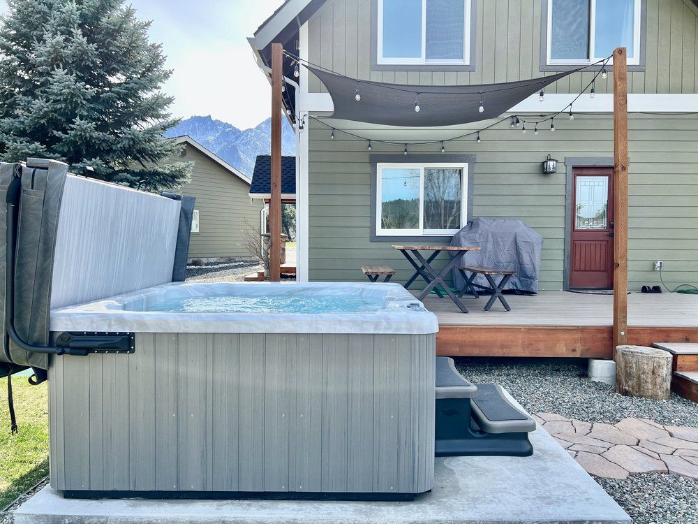 A hot tub is sitting on a concrete platform in front of a house.