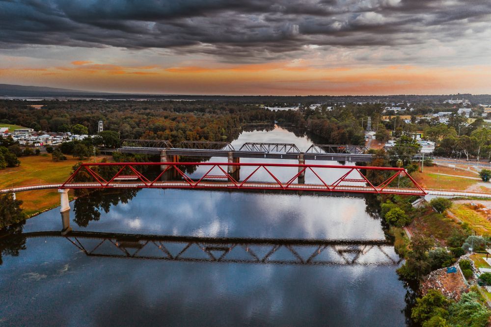 Red and Black Truss Bridges Over Dark Water, Reflecting the Sky — Premier Pest Control Wollongong In Penrith, NSW