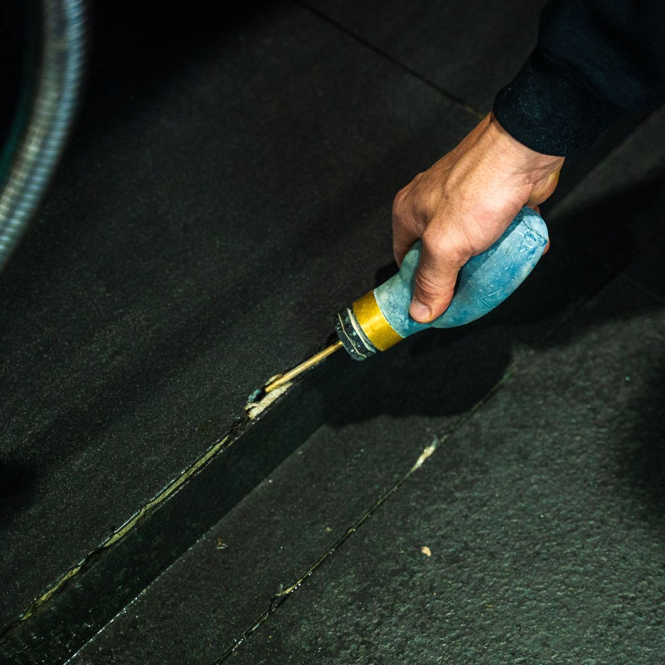 Hand Applying Sealant to a Dark Seam on a Black Surface — Premier Pest Control Wollongong In Nowra, NSW