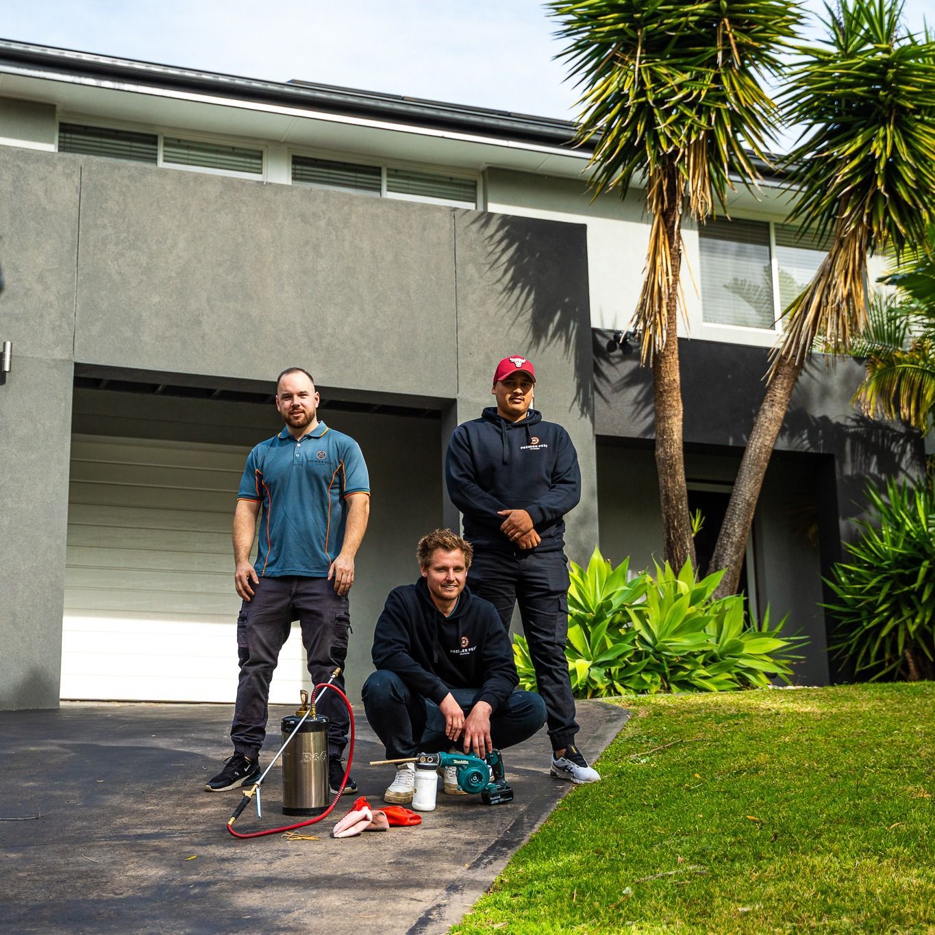 Three Pest Control Workers Pose in Front of a House With Equipment — Premier Pest Control Wollongong In Sutherland Shire, NSW