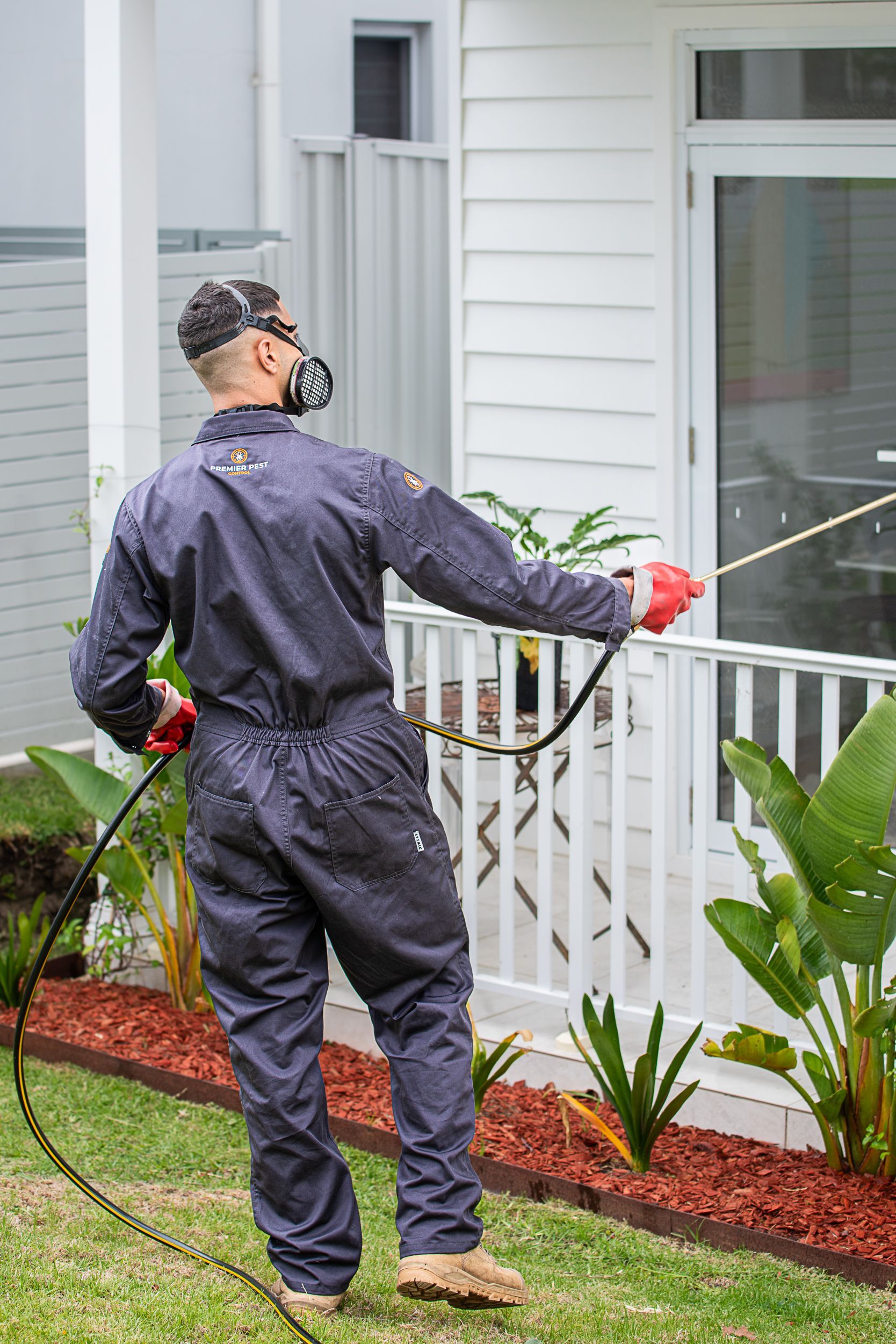 A Man In A Protective Suit Is Spraying A Chemical On The Floor — Premier Pest Control Wollongong In Wollongong, NSW
