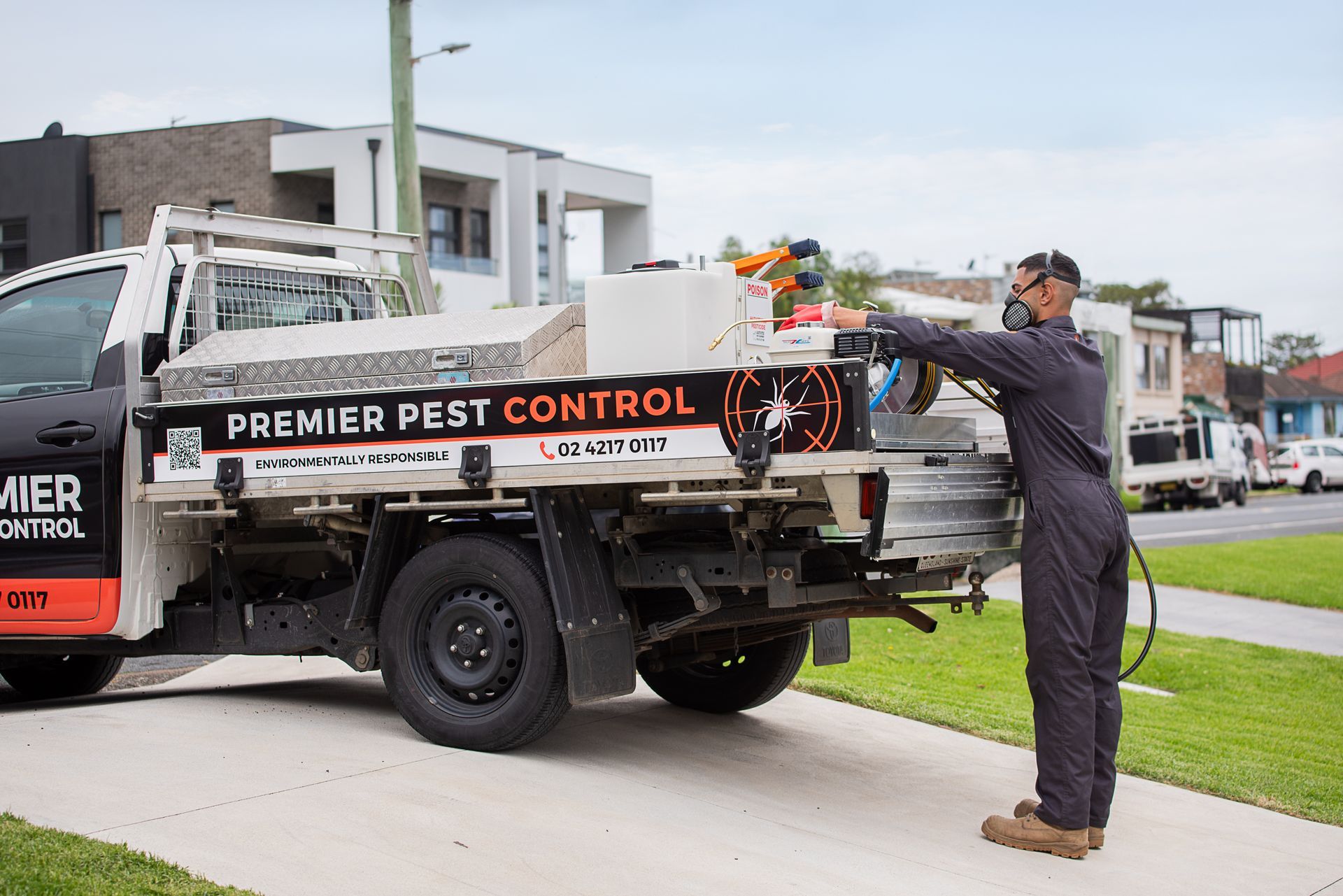A Person Is Spraying Weeds On The Side Of A Brick Wall — Premier Pest Control Wollongong In Kiama, NSW