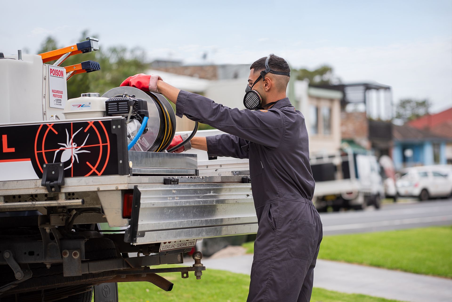 A Man In A Blue Suit Is Spraying A Wall With A Hose — Premier Pest Control Wollongong In Wollongong, NSW