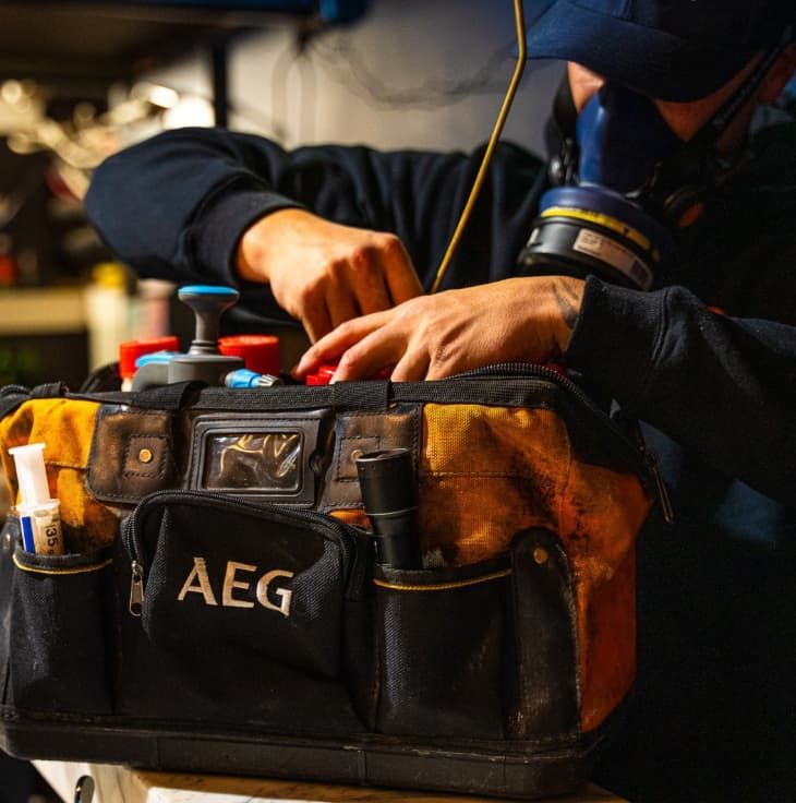 A Man Wearing A Mask Is Working On A AEG Tool Bag — Premier Pest Control Wollongong In Wollongong, NSW