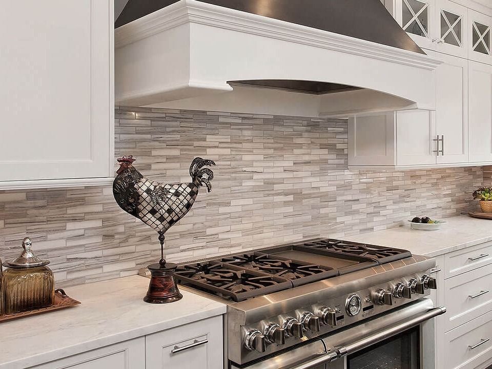 White kitchen with stone backsplash, stove, and decorative rooster statue.