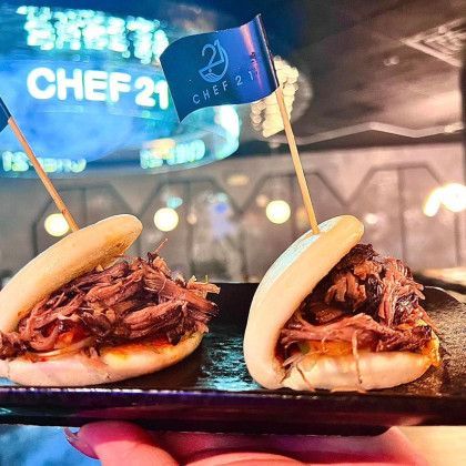 A person is holding a plate of food with two sandwiches on it.