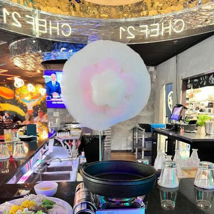 Cotton candy is being cooked in a pan on a stove in a restaurant.