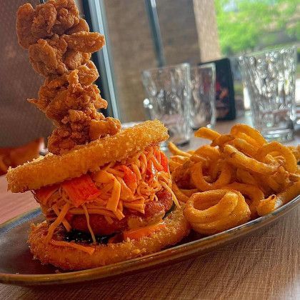 A fried chicken sandwich with french fries on a plate on a table.