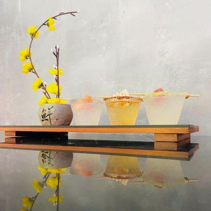 Three bowls of food are sitting on a wooden tray on a table.