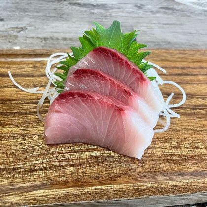 A close up of a piece of sushi on a wooden cutting board.