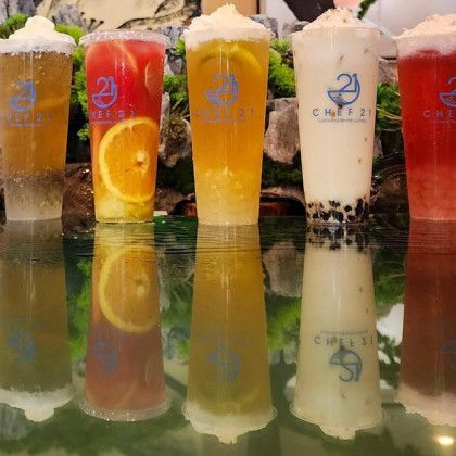 A row of cups filled with different types of drinks are sitting on a table.